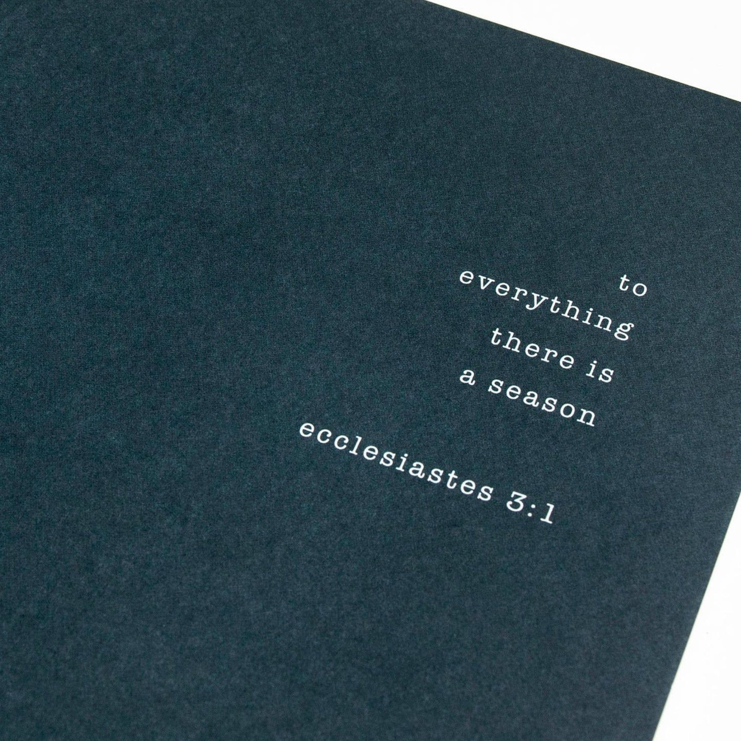 Dark blue book with white text quoting Ecclesiastes 3:1 on a white background