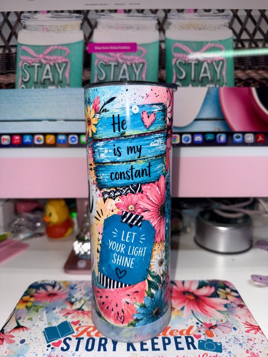 20 oz Faith Over Fear Tumbler - side view showing He is my constant and Let Your Light Shine on painted blue banner planks with pink gerbera daisies