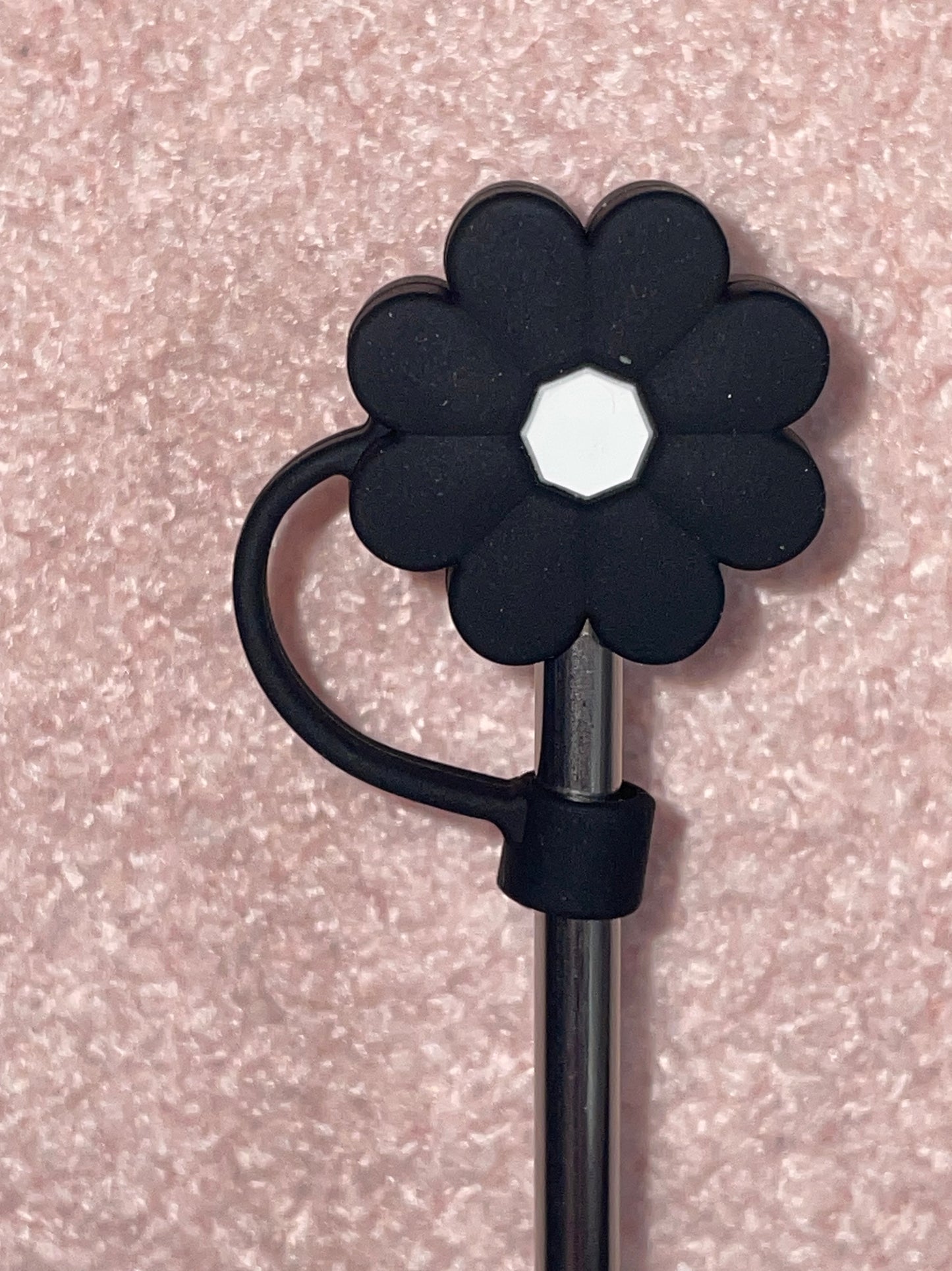 Black flower-shaped clip on a pink textured background