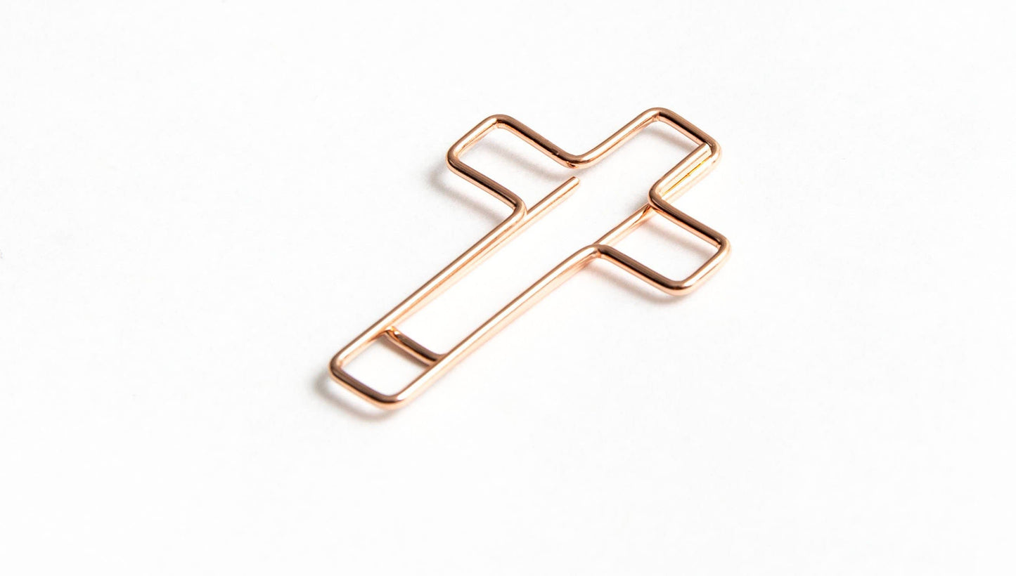Rose gold cross-shaped object on a white background