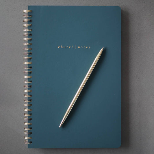 Blue notebook titled 'church notes' with a pen on a gray background