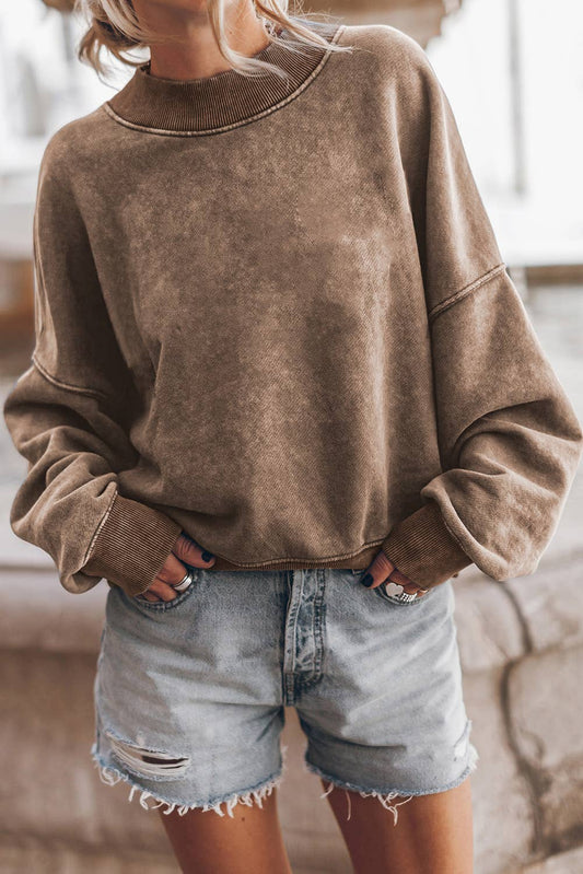 Person wearing a brown sweatshirt and denim shorts indoors