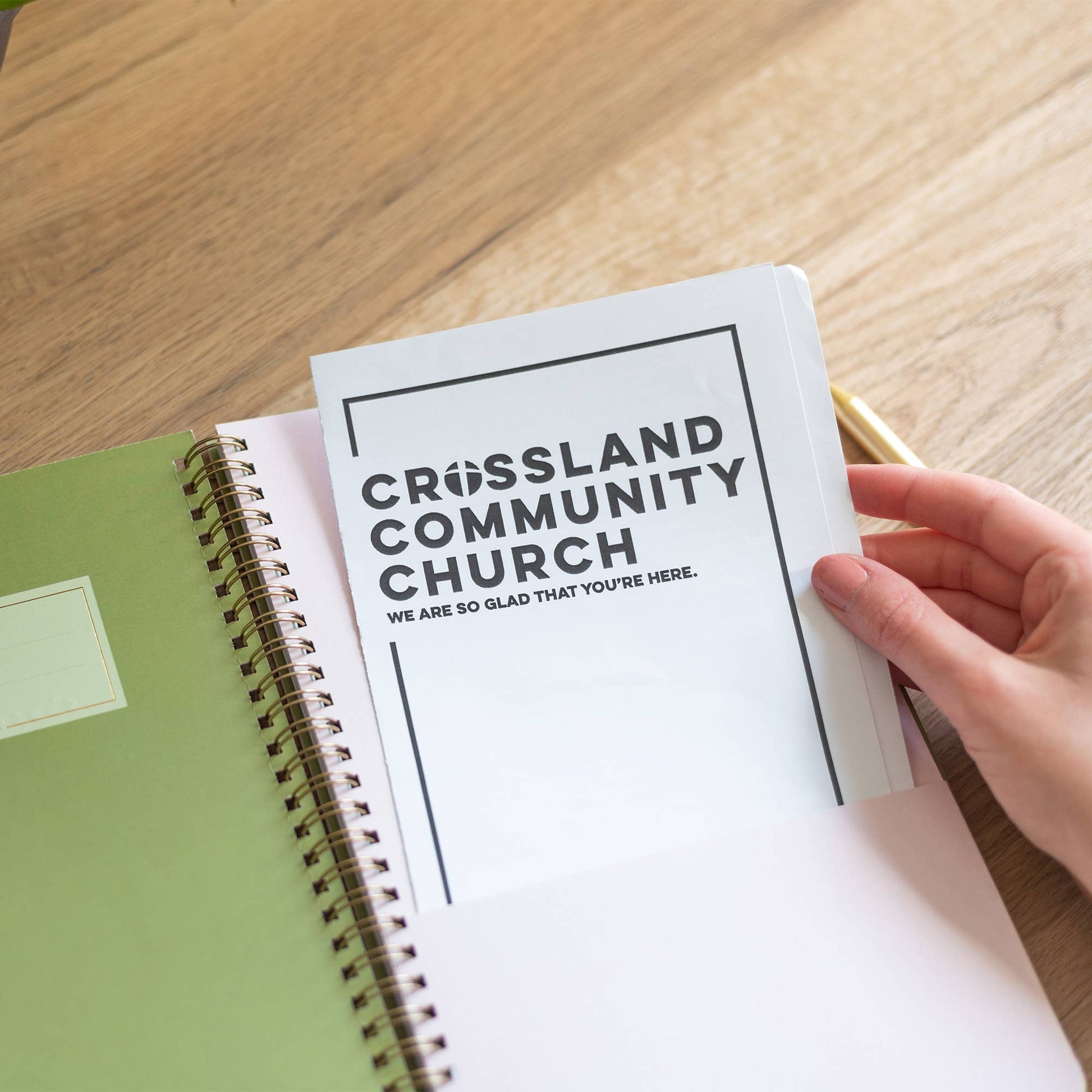 Notebook with 'Crossland Community Church' on a wooden surface
