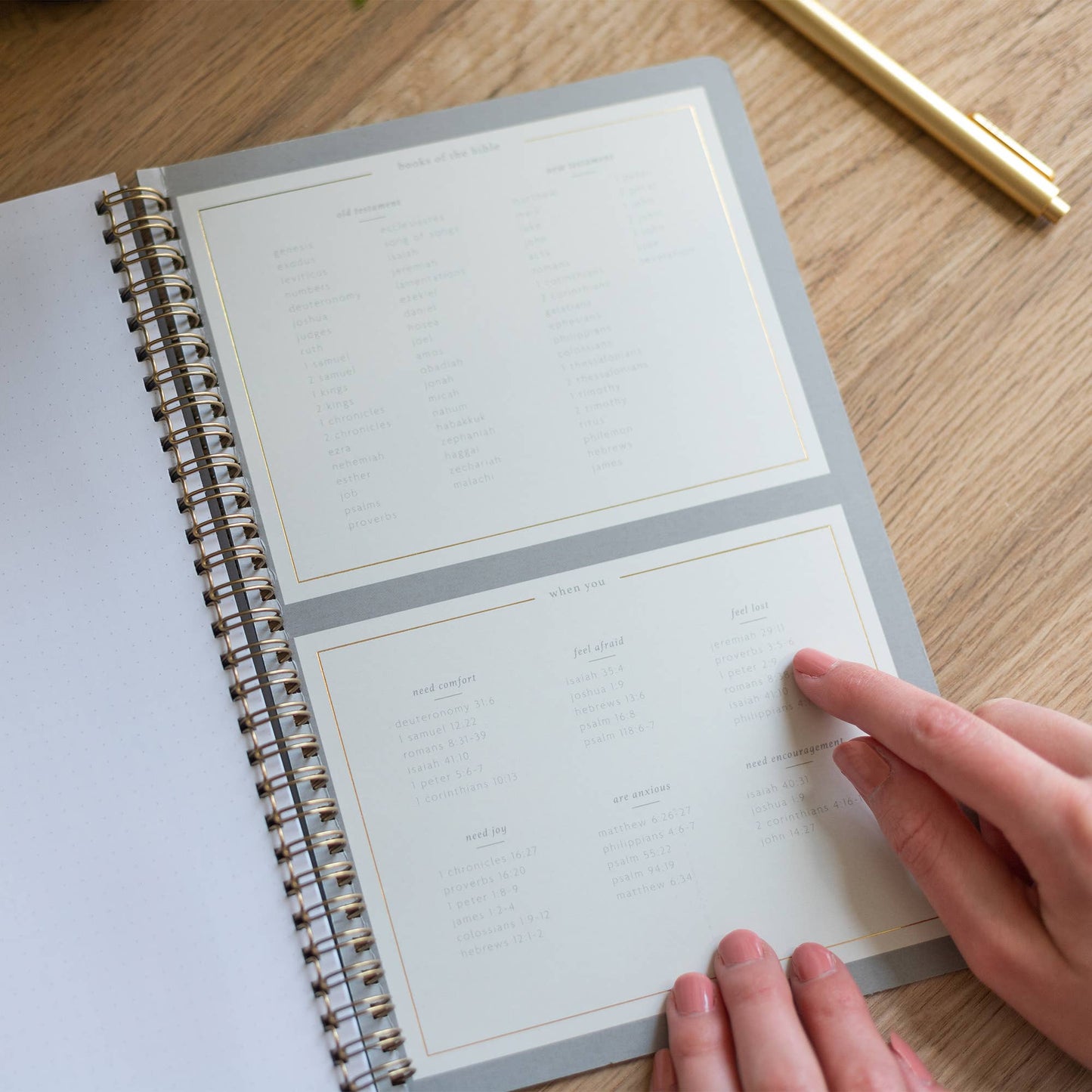 Person flipping through a spiral-bound planner on a wooden surface