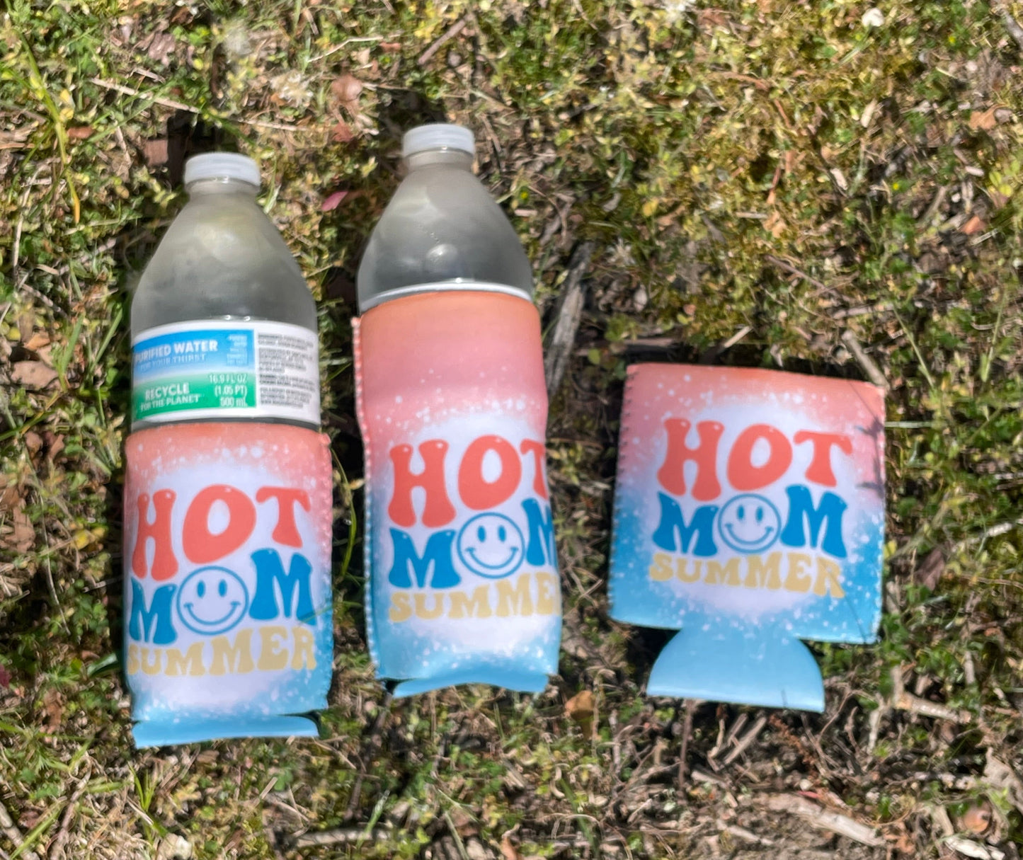 Three bottles with 'Hot Mom' branding on a grassy surface