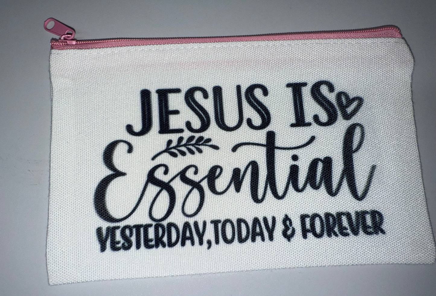 White pouch with 'Jesus is Essential Yesterday, Today & Forever' text on a gray background