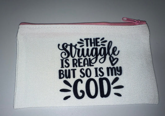 White pouch with black text 'The struggle is real, but so is God' on a gray background