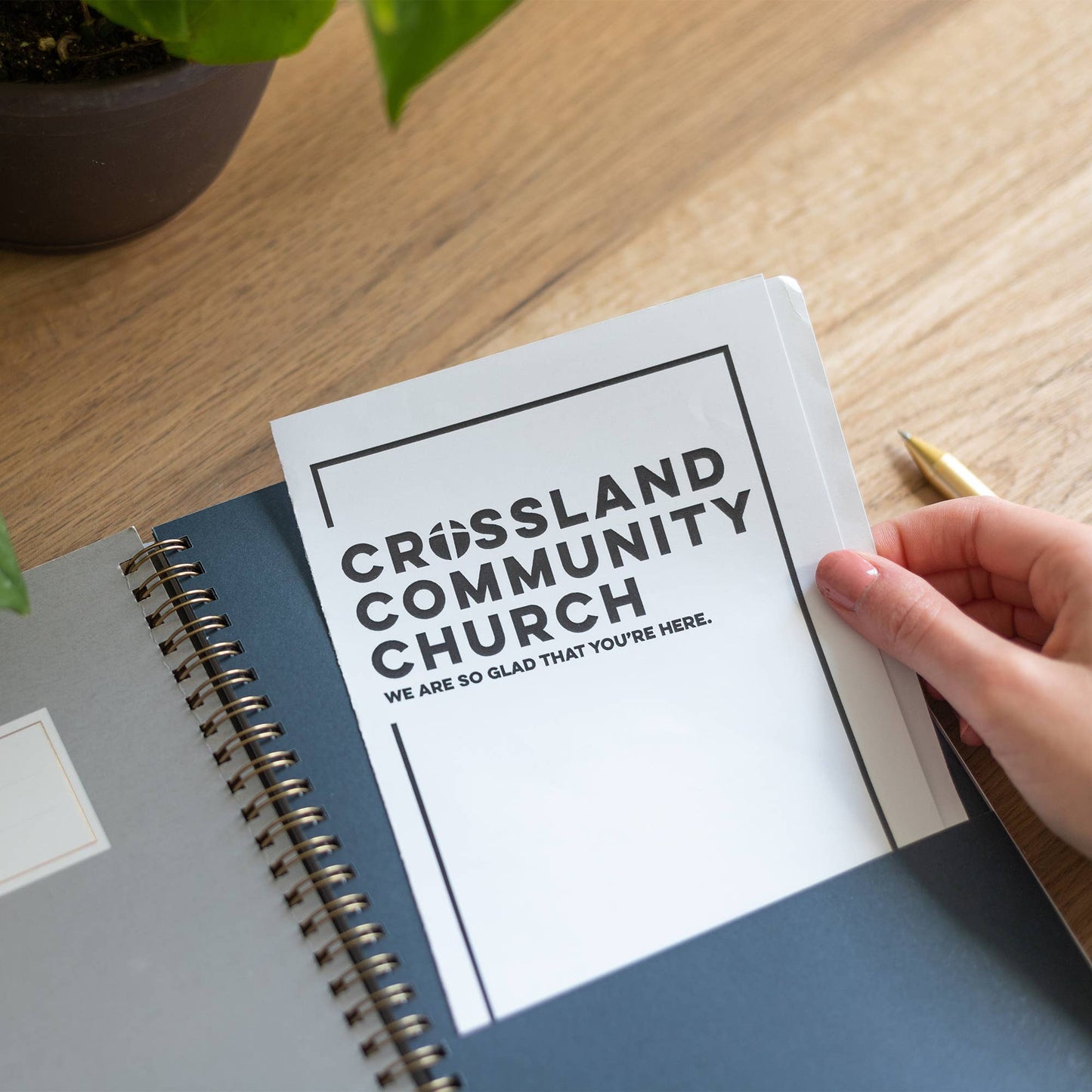 Notebook with 'Crossland Community Church' text on a wooden surface