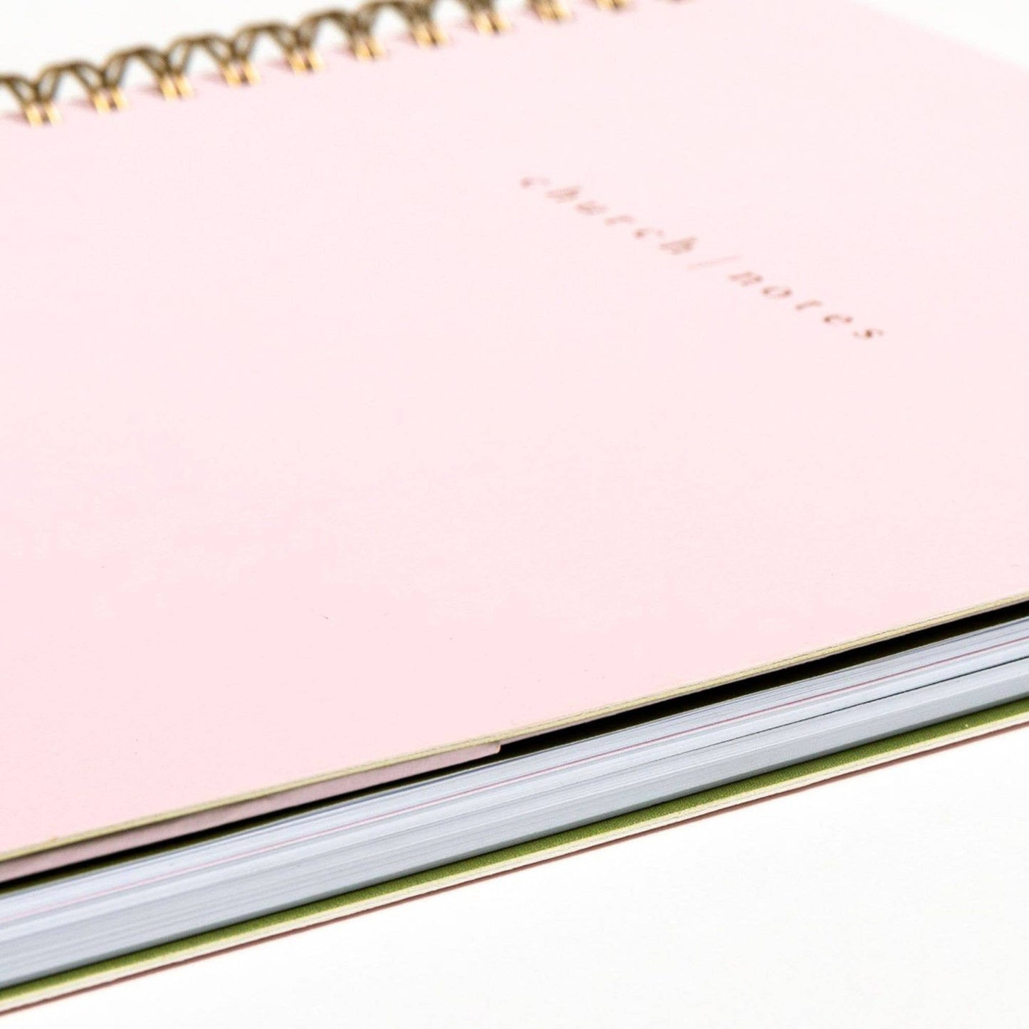 Pink notebook with gold spiral binding on a white background