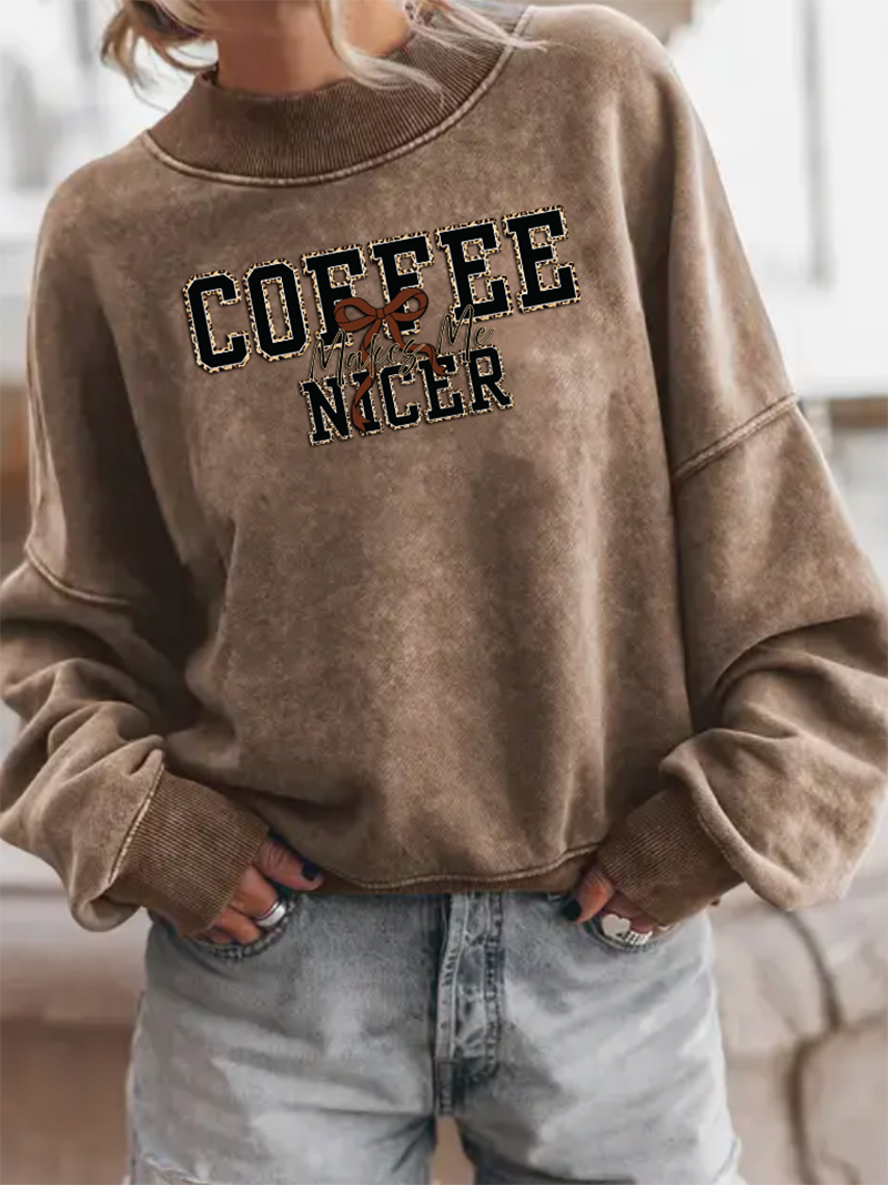 Brown sweatshirt with 'COFFEE IS NICER' text worn by a person.